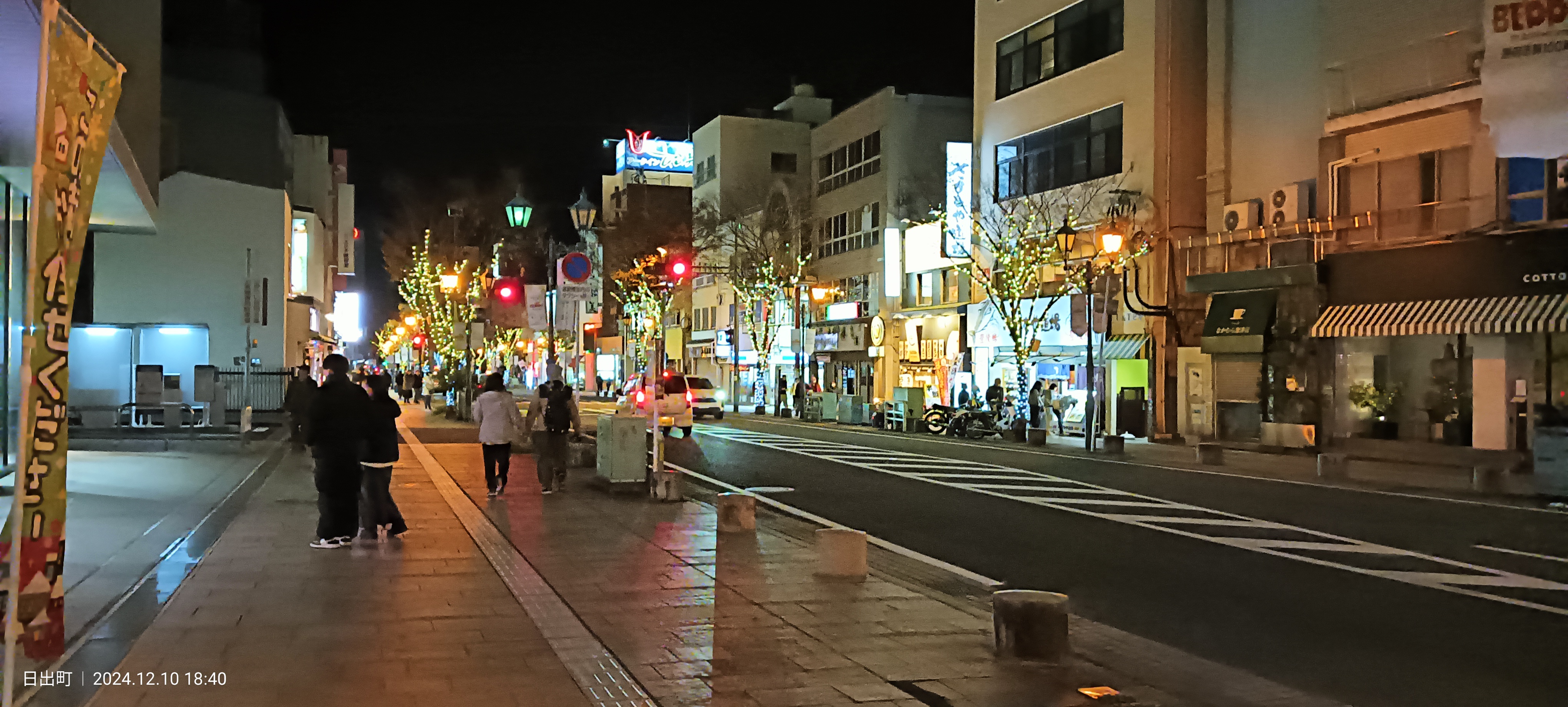 Night street in central Beppu with Christmas illumination on the trees and lit shopfronts