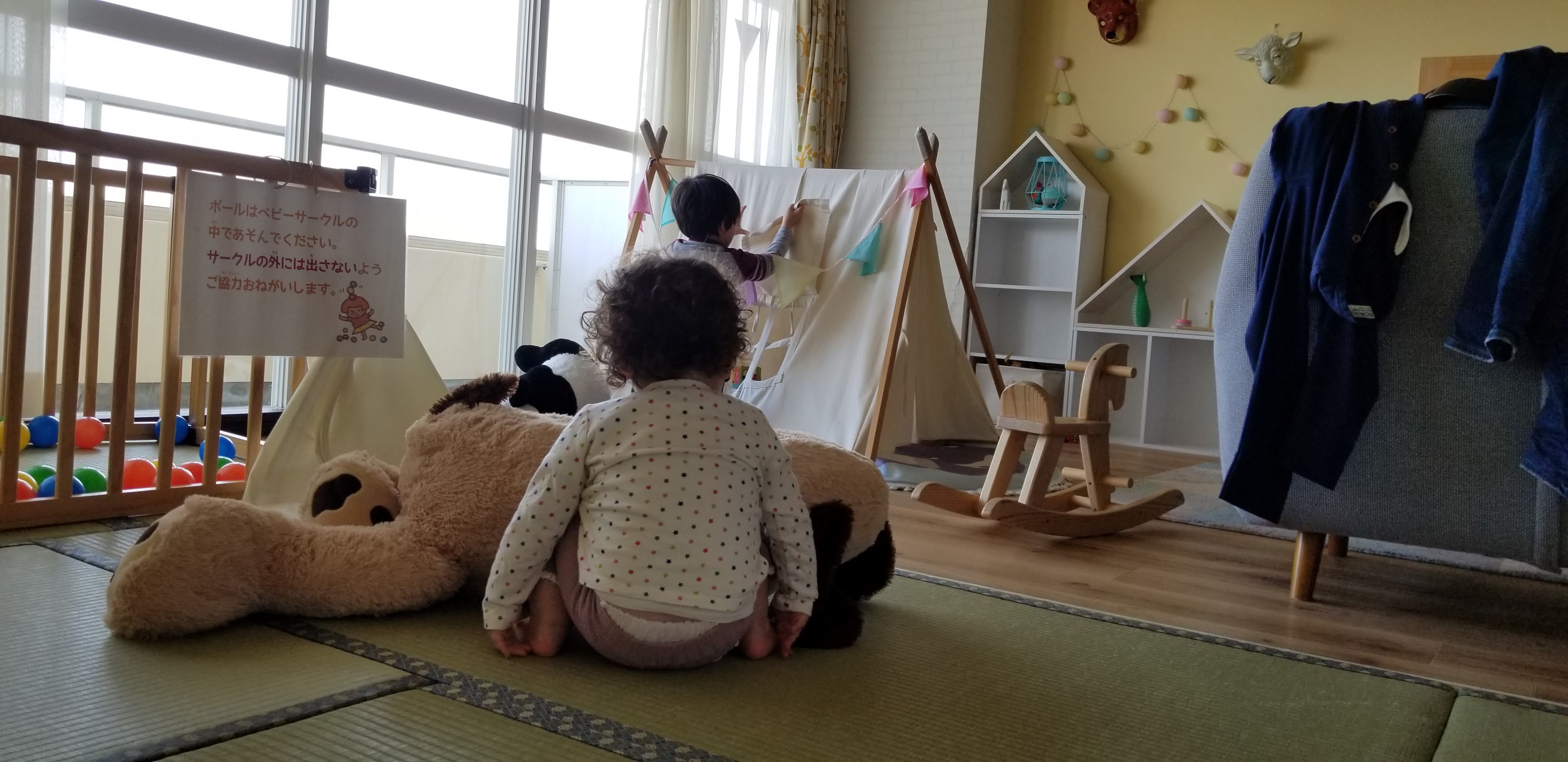 Interior of the Mahoroba Minds baby room: tatami floor with a tipi play tent, enclosed ball pit, giant stuffed panda and a wooden rocking horse for very young children