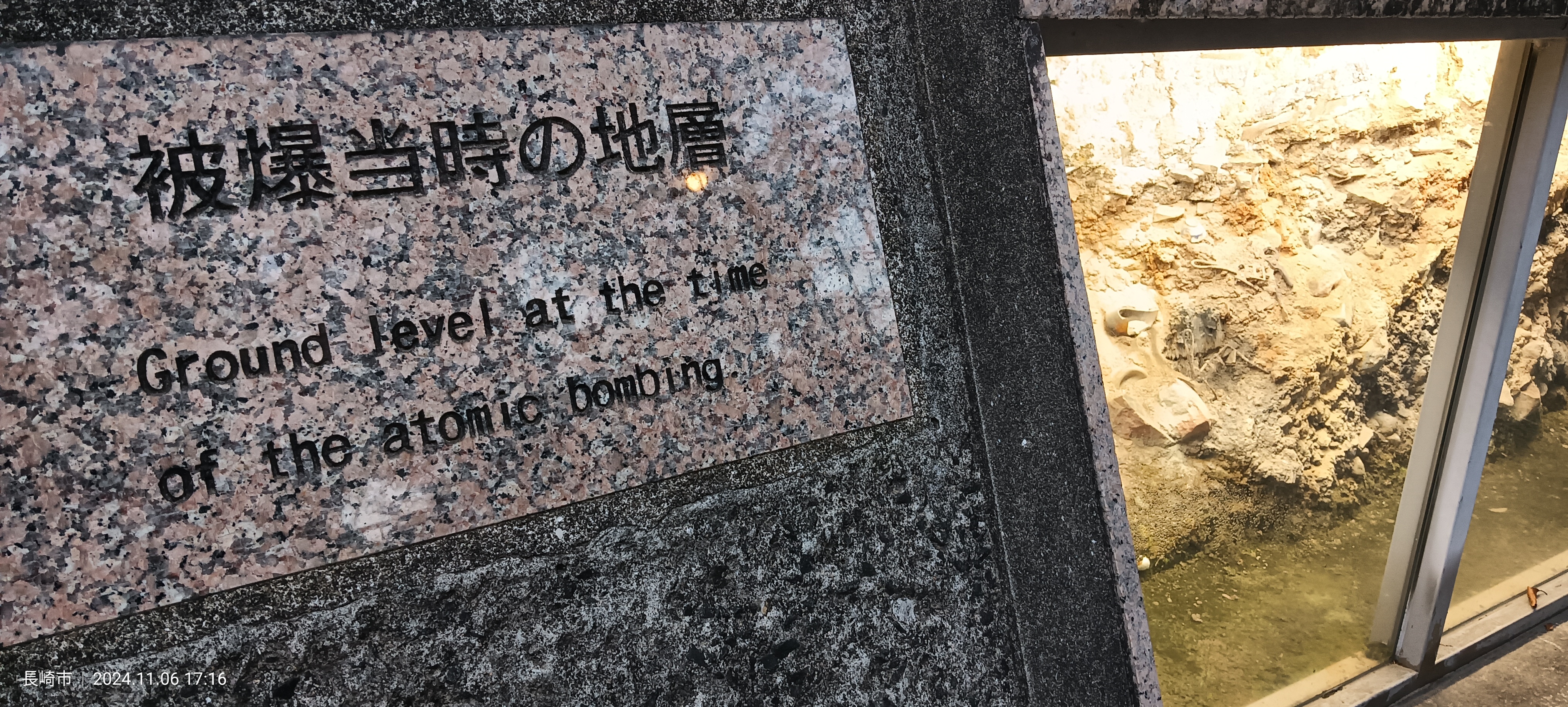 Placa en el Parque de la Paz que indica en japonés y en inglés el nivel del suelo en el momento de la bomba atómica, con los escombros originales conservados detrás del cristal