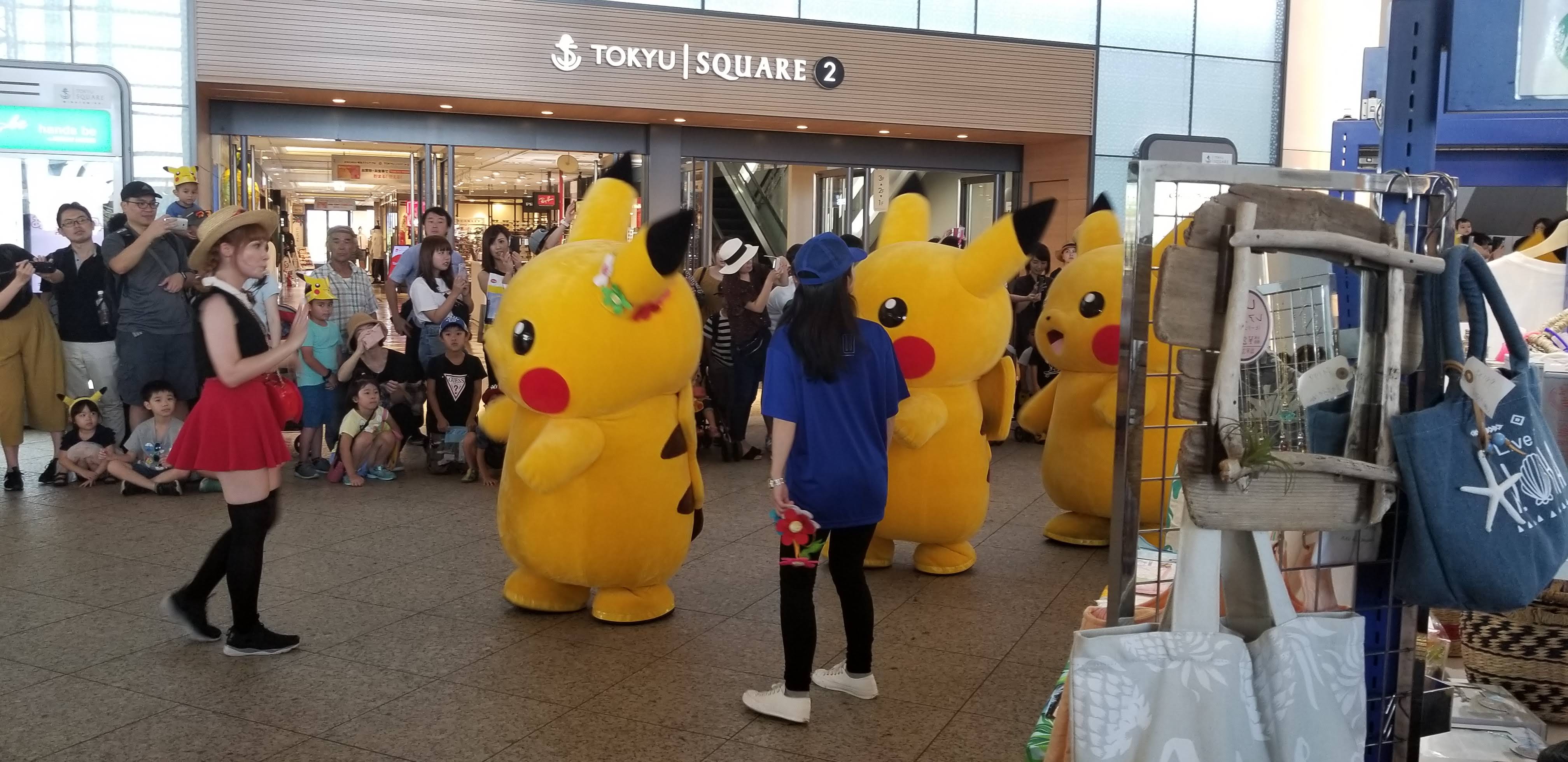 Pikachu parade at the Yokohama Outbreak, with a costumed performer leading the group in front of Tokyu Square