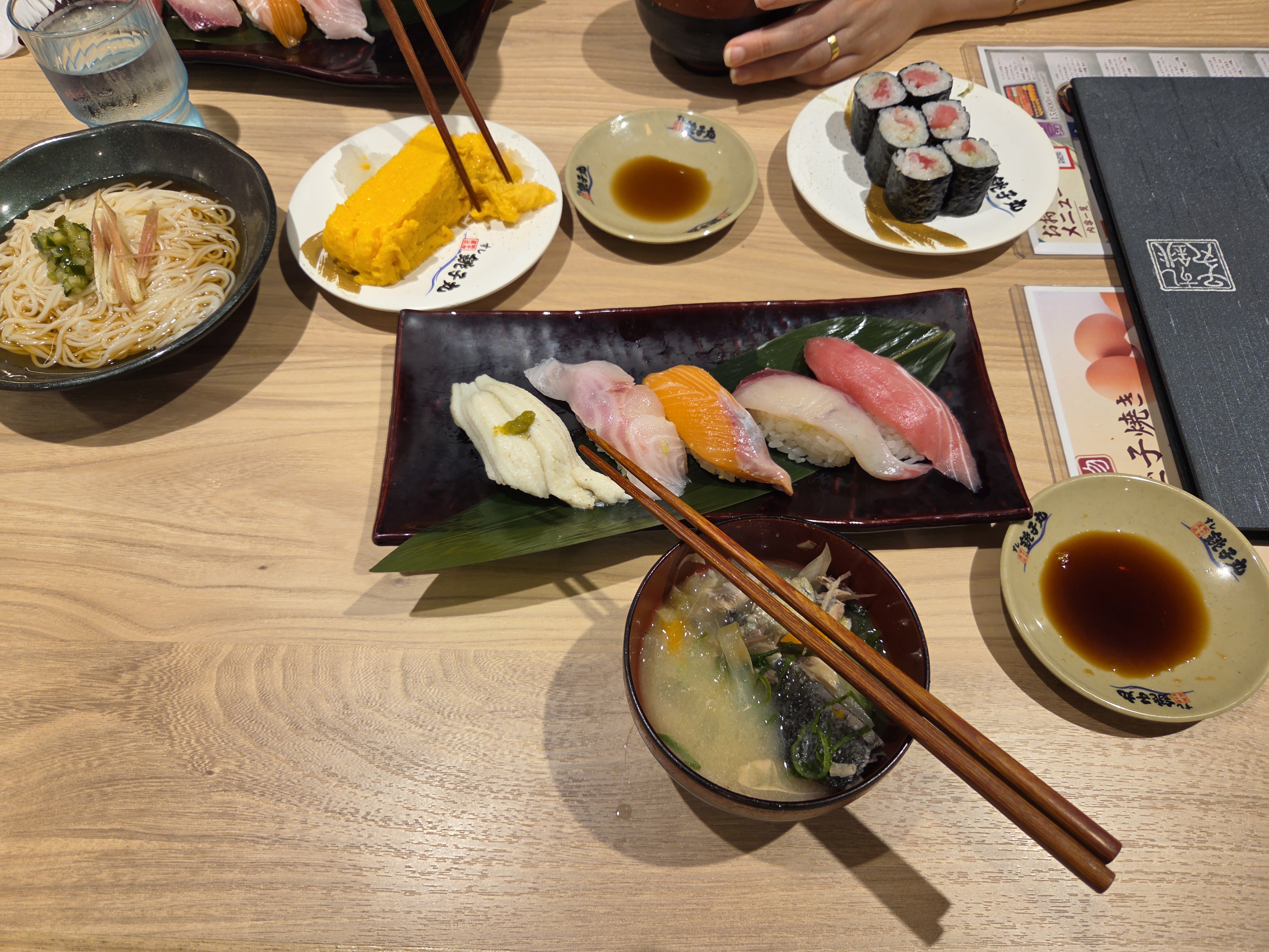 Plato de nigiri variado en un restaurante de sushi japonés: calamar, salmón, atún y otros pescados del día, con sopa de miso y maki de atún al fondo