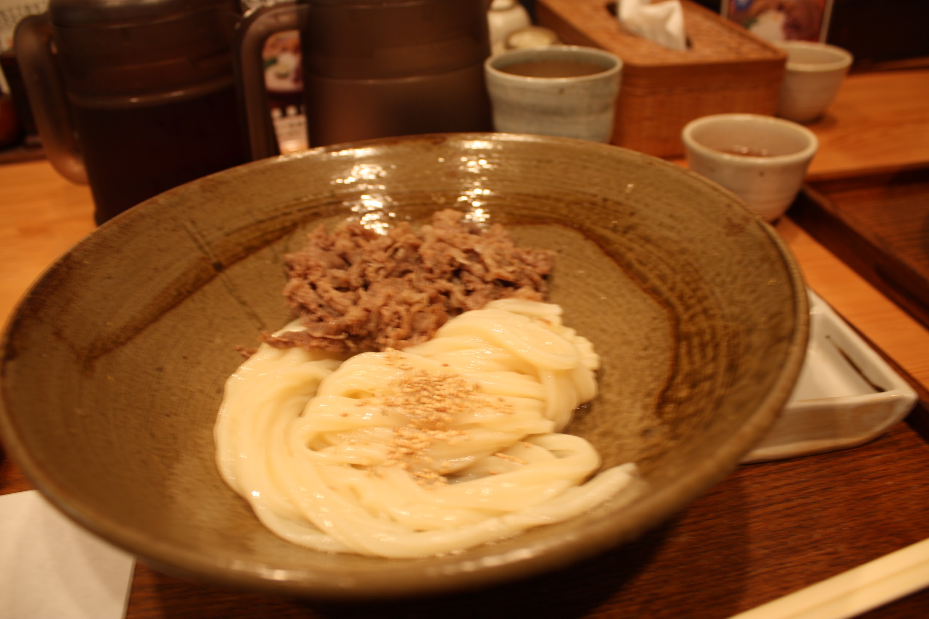 Dry beef udon in a rustic ceramic bowl at a Japanese restaurant